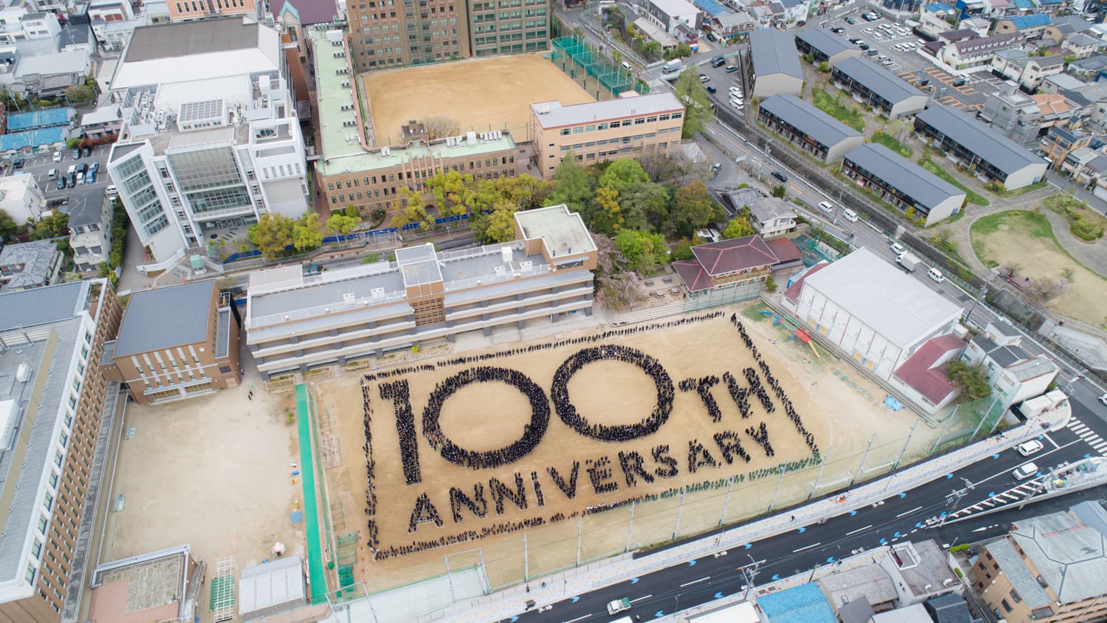 校庭に約2,700名で描いた「100th ANNIVERSARY」の人文字を、ドローンで上空から撮影した写真